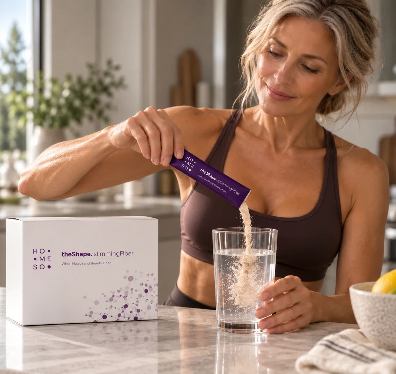 Woman pouring HoMEso theShape. slimmingFiber into a glass of water in her kitchen, with the box on the counter