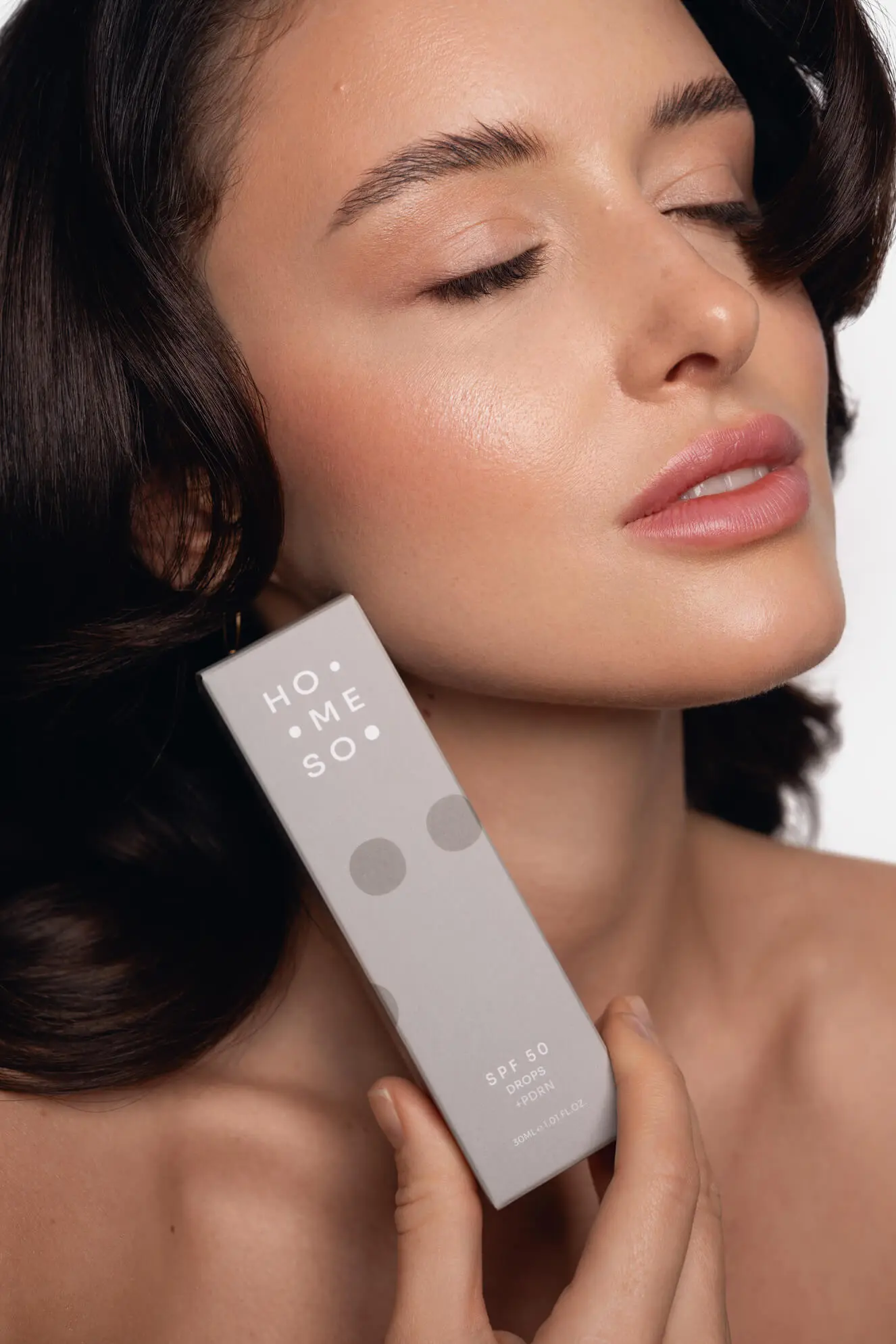 Modelka trzymająca krople HoMEso SPF 50, niezbędne do zapobiegania przebarwieniom po mikronakłuwaniu.