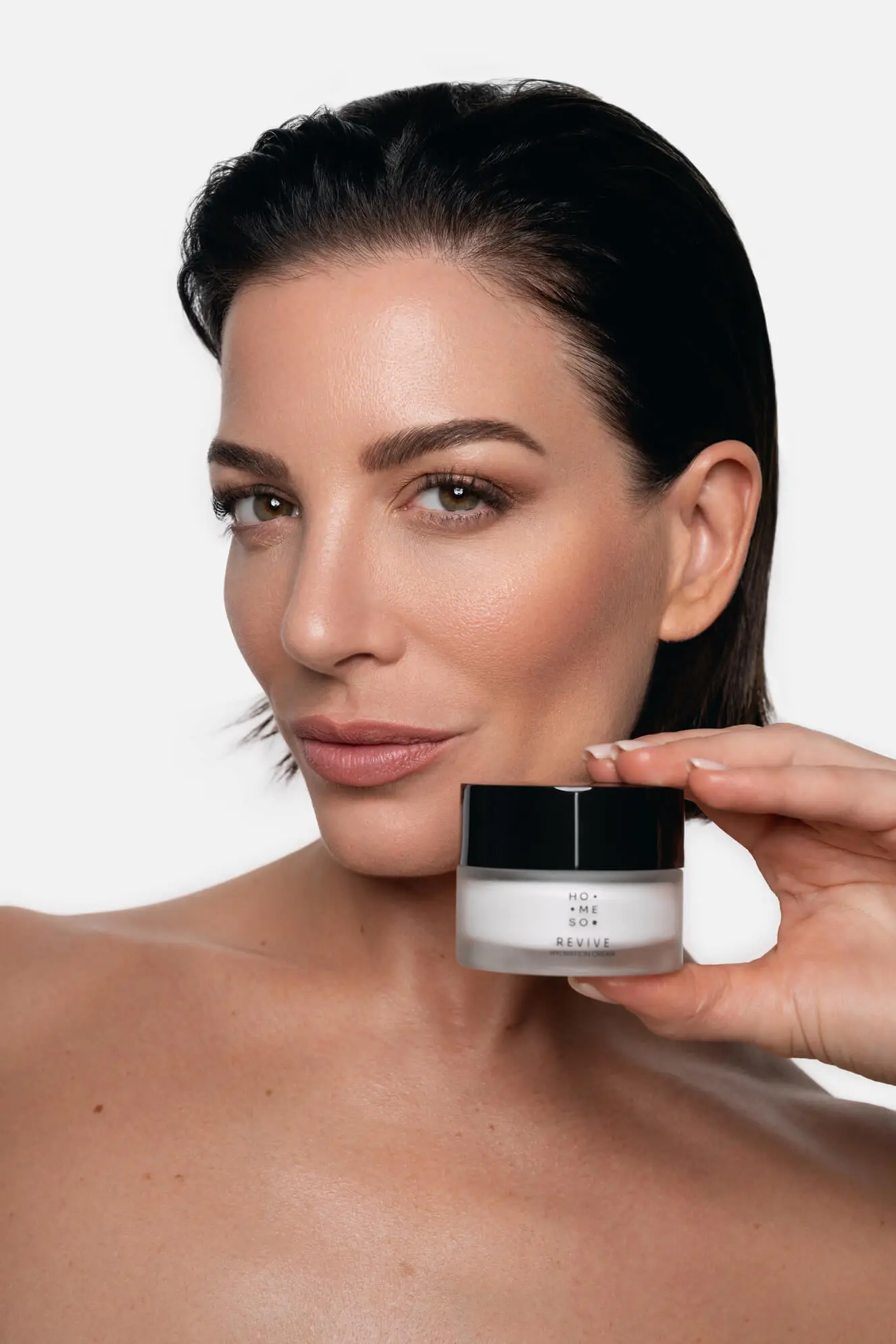 Kobieta trzymająca krem HoMEso Revive, lekki krem nawilżający odpowiedni dla wrażliwej skóry po zabiegu.