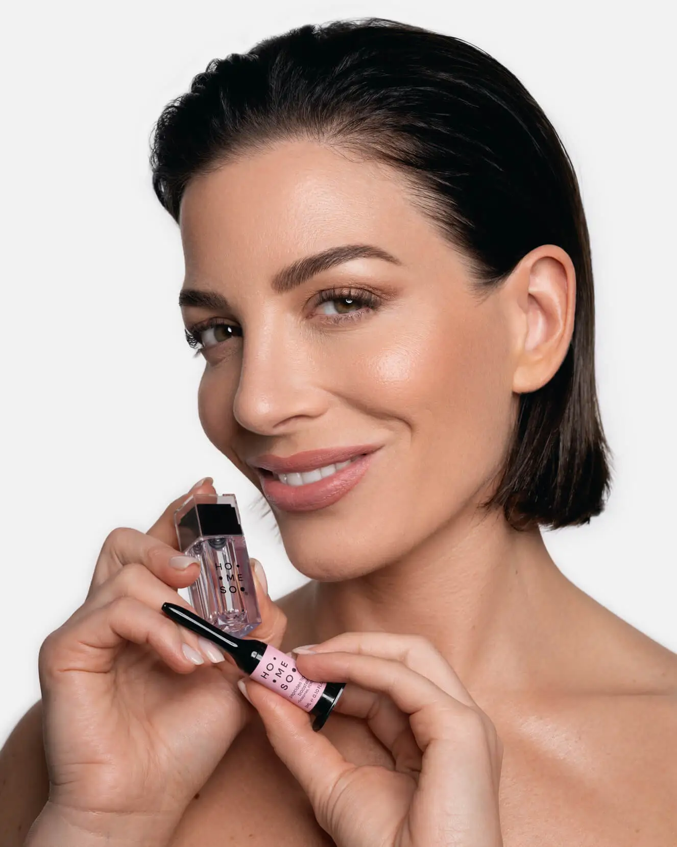 Kobieta trzymająca aplikator mikroigłowy HoMEso przed domowym zabiegiem.